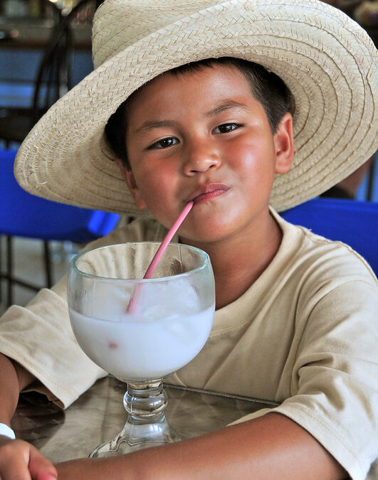 Child with a hat drinking a smoothie