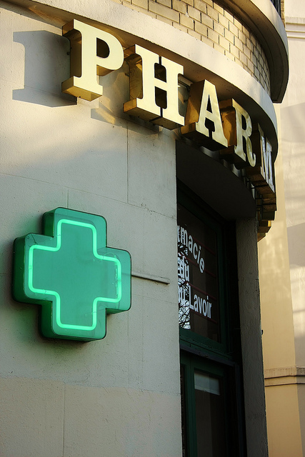 Photo of a pharmacy advertisement with a green cross and the world Pharma on a building wall