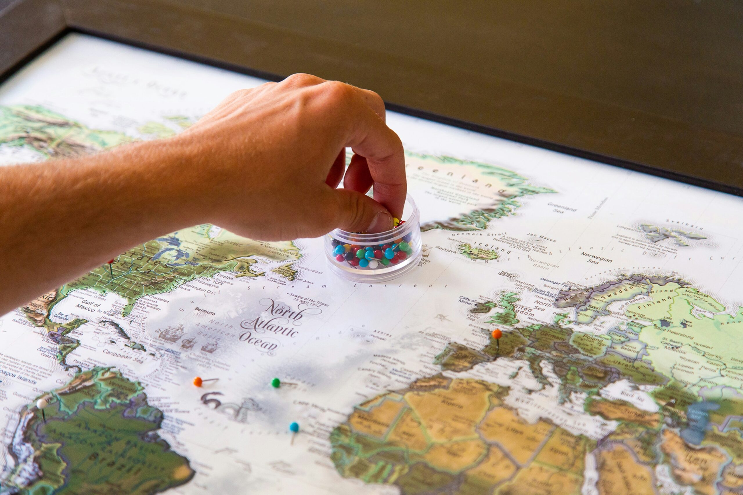 A photo showing a person placing push pins into World Map