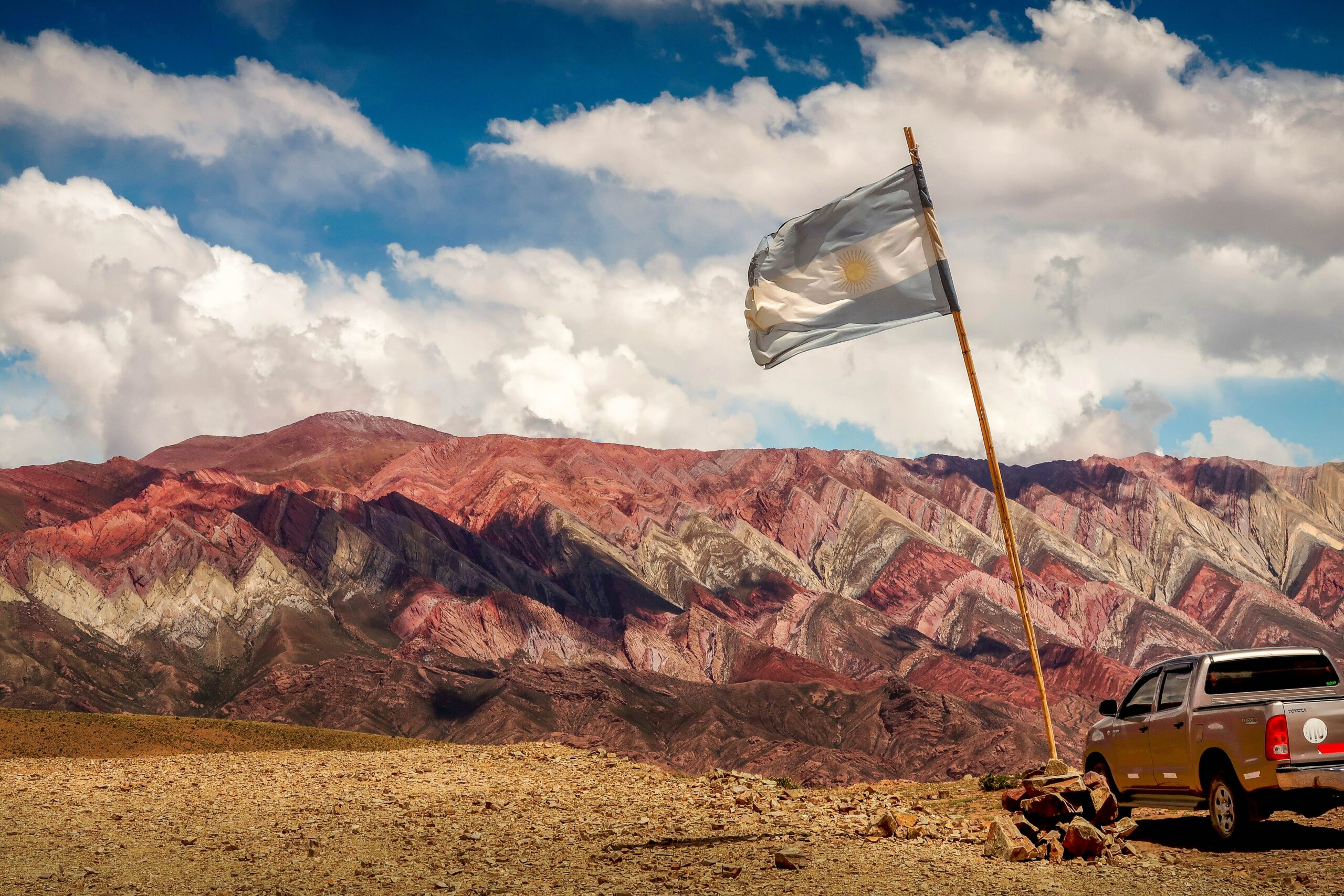 Brown rocky mountain under blue sky with Argentinian flag