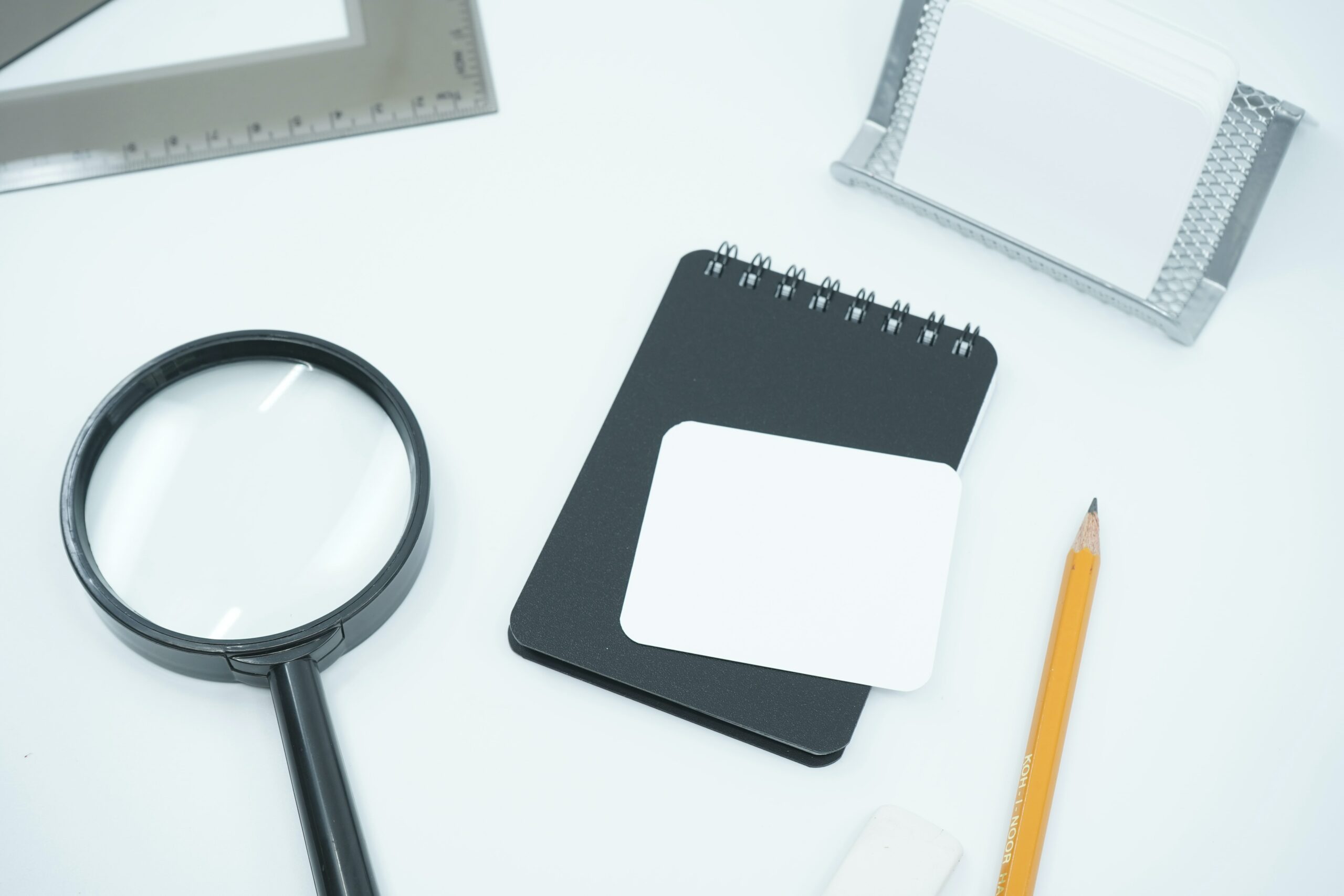 White table with a notepad, a pen, a ruler and magnifying glasses