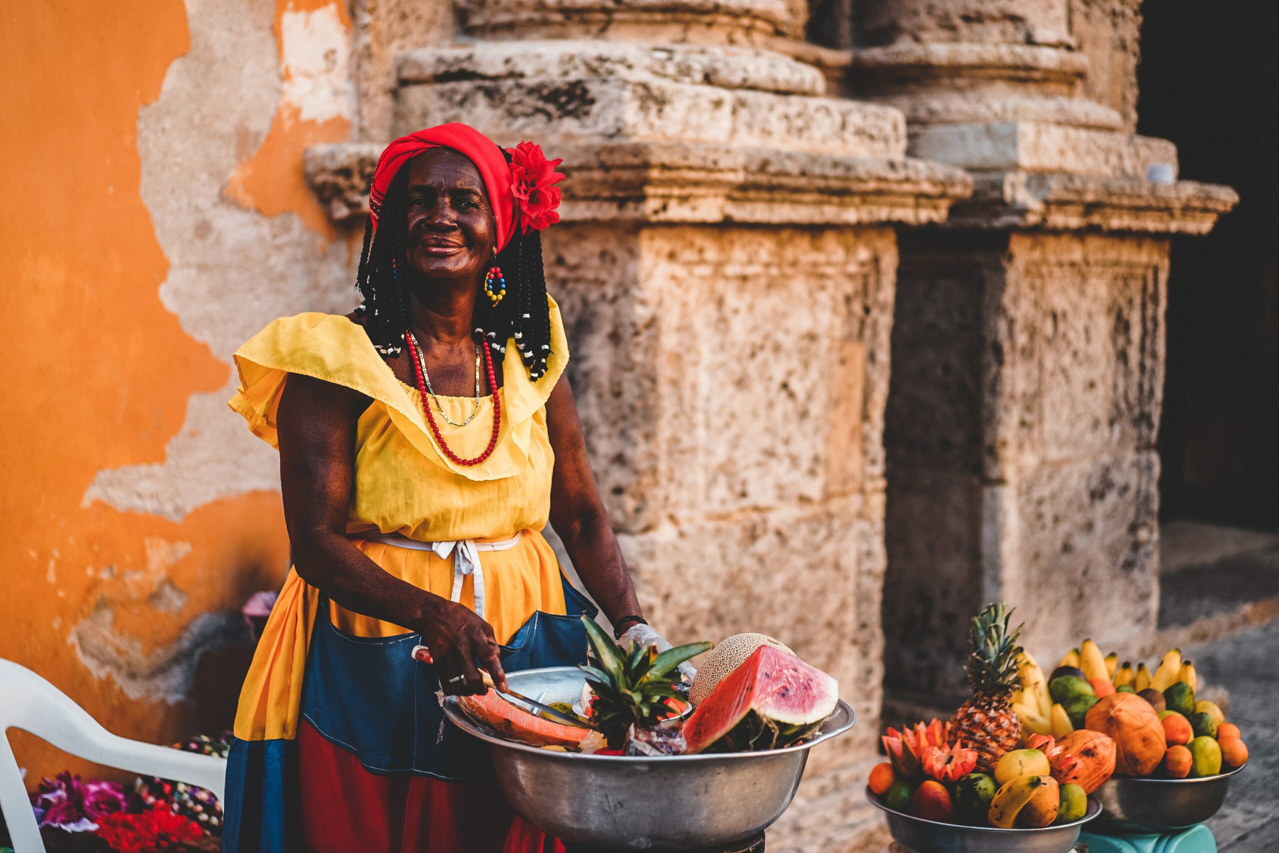 Colombian woman standing with a bucket of fruit