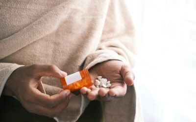 man's hand with pills spilled out of the container .